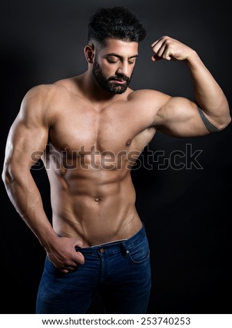 muscular male torso with six pack of a fit bodybuilder in jeans on black background