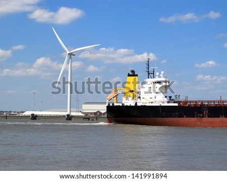 An image of a boat Passing by the wind generator on a river / Passing by the wind generator