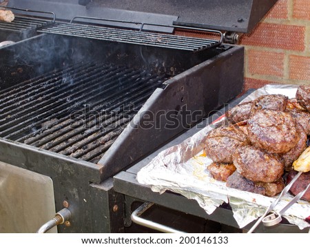 A BBQ with burgers and chicken by the side after being cooked / cooked food