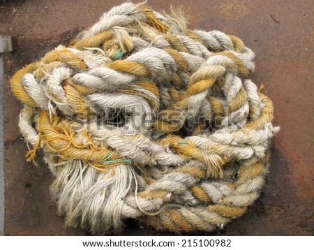 A view of a coil of rope with gold and white twine / Coil of old rope