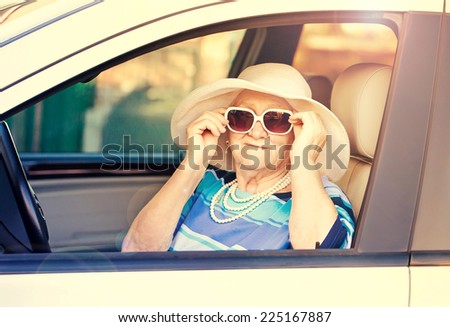 old woman in sunglasses sitting in the car .