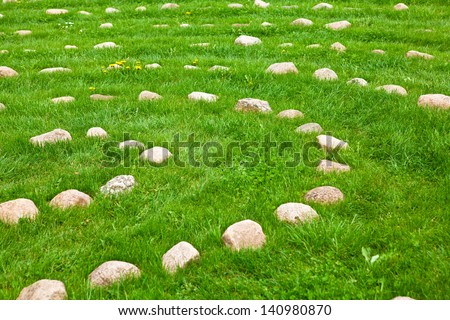 Rows of stones arranged in concentric circles lying in lush green grass, closeup view