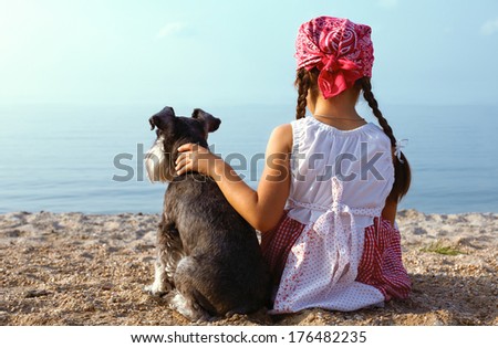 beautiful girls embracing her dog looking at the sea