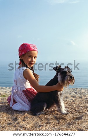beautiful little girls embracing her dog looking at the sea