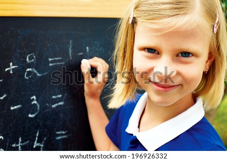 beautiful schoolgirl decides on a blackboard mathematical tasks