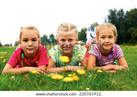 Image of happy group girls lying on a green grass