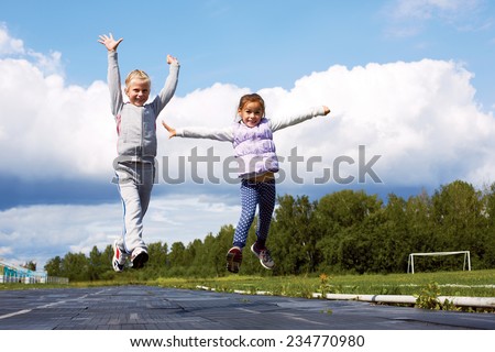 school-age girls are jumping on the stadium during a training session