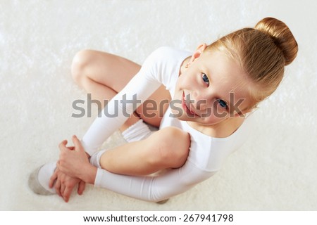 Children sport. Little sporty girl sitting on the white carpet. top view