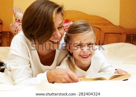 Mom reading a book to little daughter.