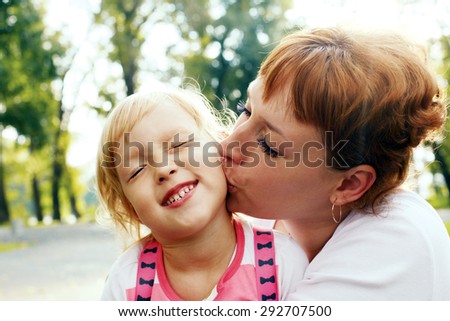 An affectionate mom kissing her little daughter. Happy daughter laughing.