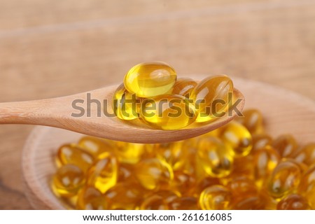 Cod liver oil omega 3 gel capsules isolated on wooden background. Vitamin capsules