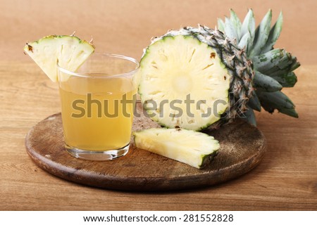 sliced pineapple with a glass of pineapple juice on wooden board