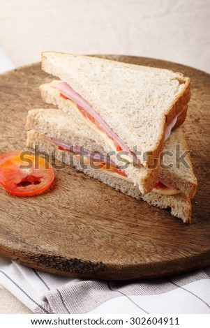 fresh sandwich with ham, cheese and tomato on wooden board