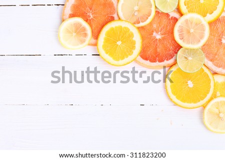 Citrus fruits cut background- oranges, lemons, limes, grapefruit on a wooden background