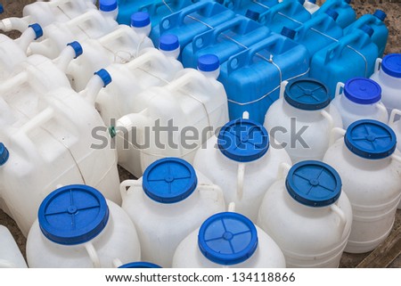 White and blue plastic gas cans (fuel container) in an open market under natural lights