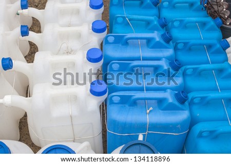 White and blue plastic gas cans (fuel container) in an open market under natural lights
