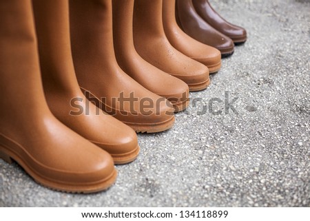 Plastic rubber boots for sale on an open market under sunlight