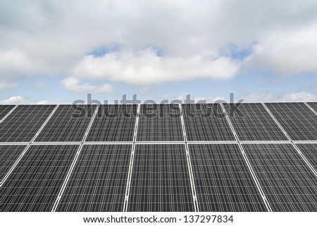 Field with many solar panels in front of a blue sky