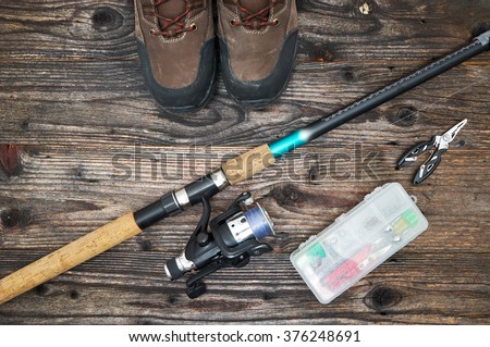 fishing tackles and fishing gear on wooden background, top view