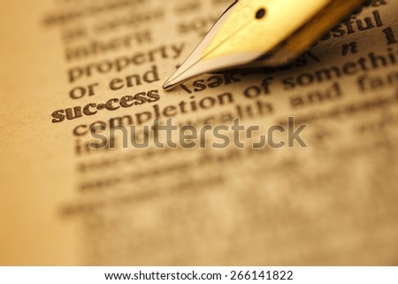 Success pen nib pointing to the words in the dictionary, shot with very shallow depth of field,