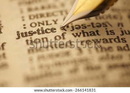 Justice pen nib pointing to the words in the dictionary, shot with very shallow depth of field,