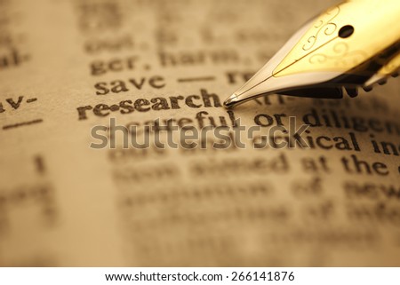 Research pen nib pointing to the words in the dictionary, shot with very shallow depth of field,