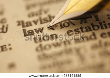 Law pen nib pointing to the words in the dictionary, shot with very shallow depth of field,