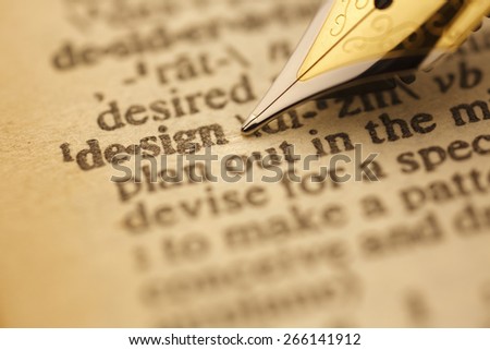 Design pen nib pointing to the words in the dictionary, shot with very shallow depth of field, Gold tone