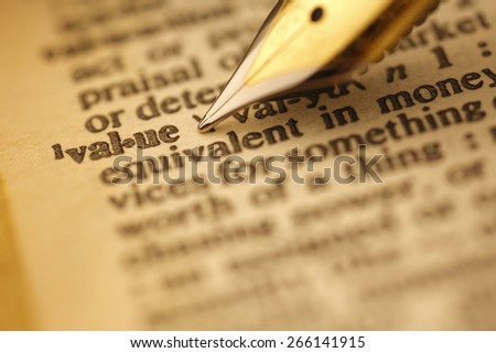 Value pen nib pointing to the words in the dictionary, shot with very shallow depth of field,