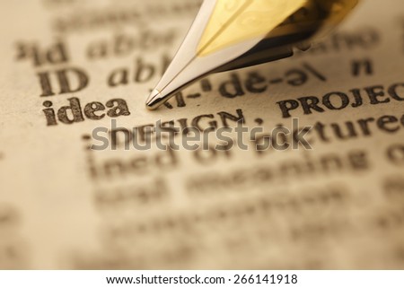 Ideas pen nib pointing to the words in the dictionary, shot with very shallow depth of field,