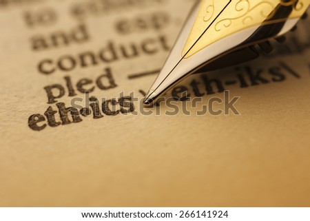 ethics pen nib pointing to the words in the dictionary, shot with very shallow depth of field,