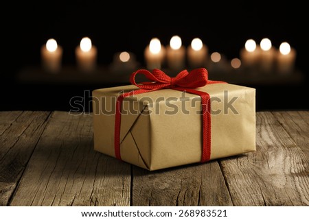 Elegant Christmas gift wrapped on Wood table, fairy Candlelight light background. Selective focus.