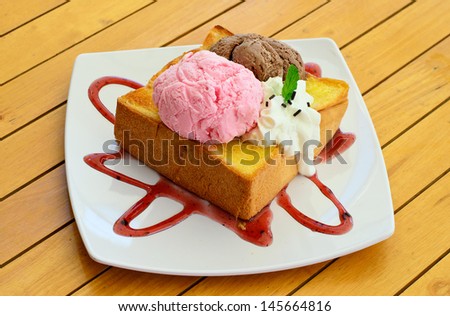 Honey toast and whipping cream with chocolate and strawberry ice cream on a wood desk