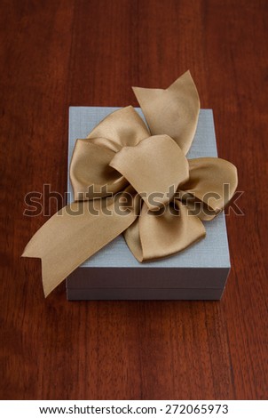 Holiday Gift Packed into Grey Box with Ribbon on Glossy Wooden Table. Design elements.