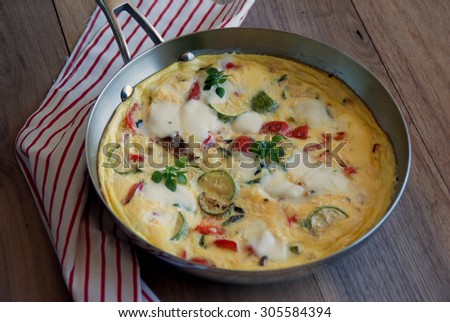 Frittata with Grilled Summer Vegetables baked in stainless steel pan, served in the garden on summer sunny morning. Idea for Breakfast. Summer Meal.