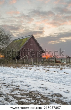 Animal shelter at sunrise seen from the side of a gravel and snow covered road.