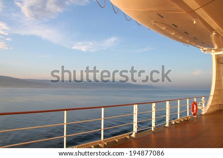 On the open deck of a cruise ship on a calm day, with the coast in the distance.