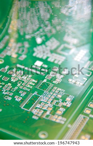 Bare printed circuit board, PCB, in green photo resist undergoing inspection.