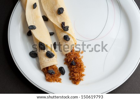 Rolled Pancakes with grated coconut filling, decorated with dried grapes