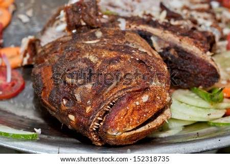 big fried whole fish. close up of huge fish fried with teeth and eyes in focus. monster fish. cooked fish. Fish curry. Asian fish. wired food. healthy fish food. omega 3. fish for good health