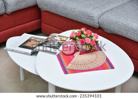 Modern Red sofa made of jute material and white center table with flowers and candle in apartment living room. Center coffee table.