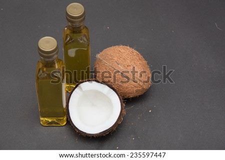 Coconuts cut in half and whole coconuts. Two bottles of coconut oil.