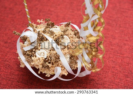 Basket full of dried flowers with white and golden ribbon isolated on red jute background. Wedding flower basket.Decoration bouquets of dried flowers.DRIED FLORAL BOUQUET IN A BASKET