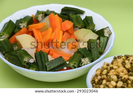 fresh vegetables carrot ladies finger potatoes cut up slices for making sambar India in bowls and sprouted seeds of green gram isolated on green