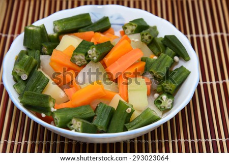 fresh vegetables carrot ladies finger potatoes cut up slices for making sambar India in bowls isolated on bamboo mat