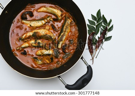sardine fish cooked. Traditional hot and spicy fish curry Kerala India with dried red chilly and green curry leafs. Very popular coastal food eat with with tapioca or rice.