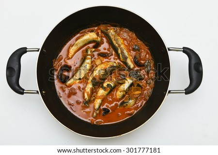 sardine fish cooked. Traditional hot and spicy fish curry Kerala India in a pan with dried red chilly and green curry leafs. Very popular coastal food eat with with tapioca or rice.