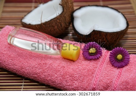 Fresh coconut cut open in half with extra clear and pure coconut oil. tropical Spa beauty exotic tropical flowers towels soap setting. Wellness & spa massage alternative treatment with coconut oil