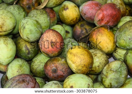 Yummy pile of ripe mangoes in a market stall .Sweet mangoes green and yellow cut open.The mango is now cultivated in most frost-free tropical and warmer subtropical climates.Major production in India