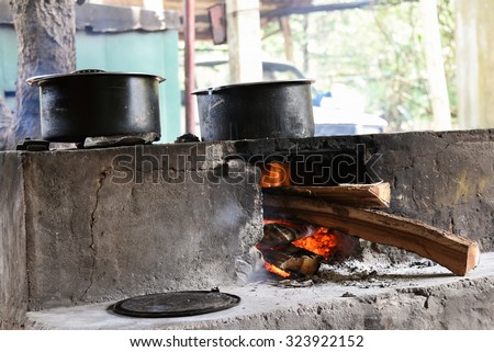 Traditional way of making food on open fire in old kitchen in a village hotel, Kerala India. Pots and pans on the stove over a natural fire for cooking. Rural kitchen using bio wood fuel for cooking